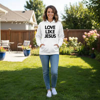 Woman wearing a white hoodie with 'LOVE LIKE JESUS' text in a backyard setting.