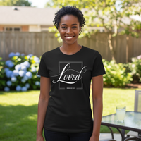 Woman wearing a black t-shirt with 'Loved' text in a garden setting